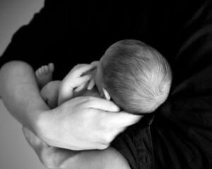 un bébé dans les bras de son pere